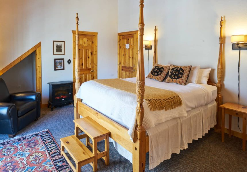 Four poster queen bed in a room with carpet floors and an electric fireplace