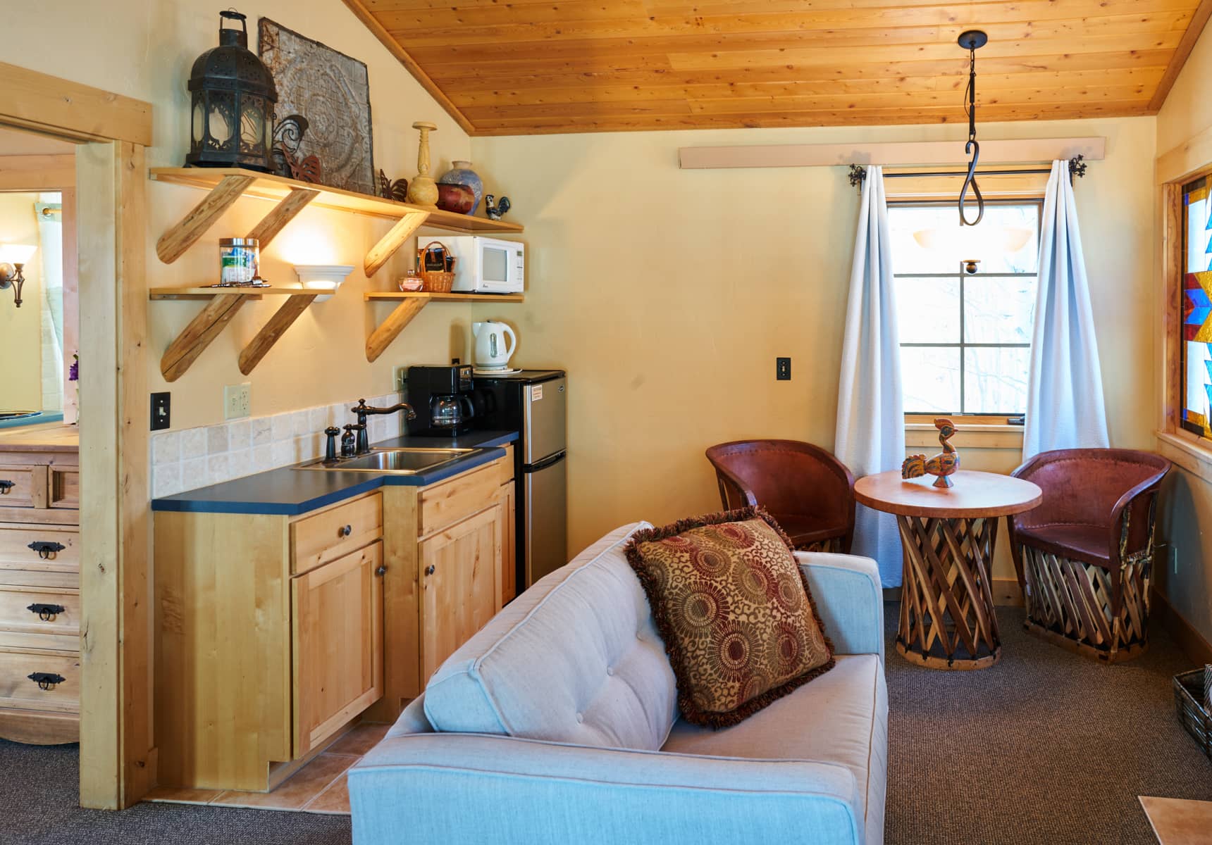 Seating area, kitchenette, and dining table for two in the Mariposa Cabin