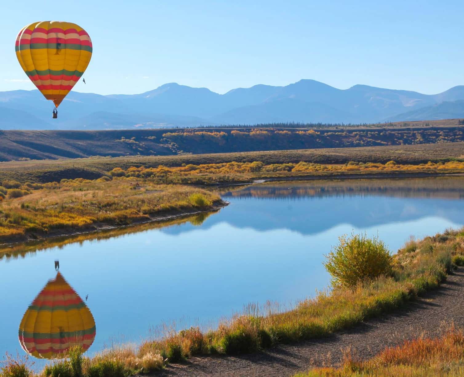 Hot air balloon floats above a small river